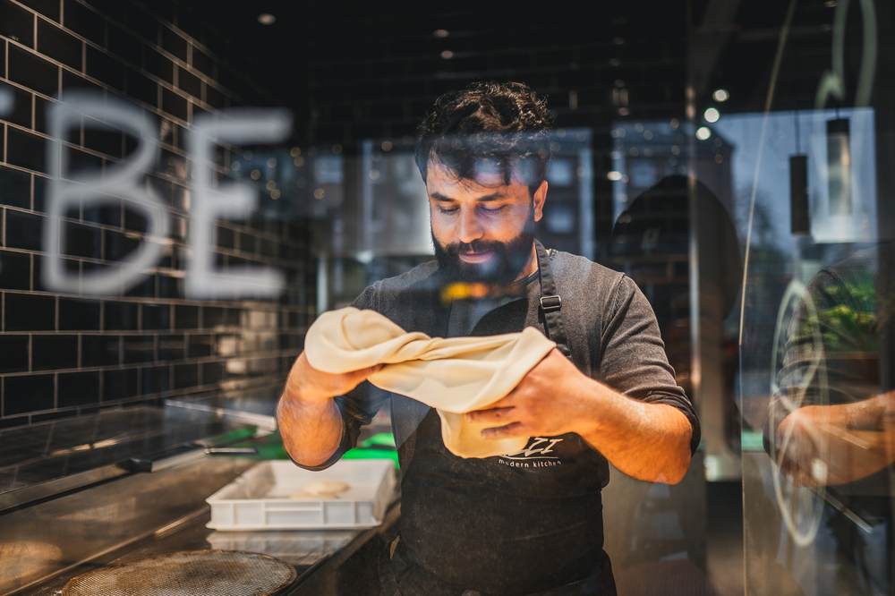 Pizzabäcker zieht Teig in der Showküche